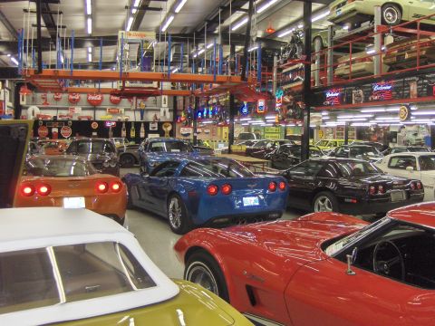 1979 Chevrolet Camaro - A collection of sports cars are parked inside a well-lit garage with storage shelves overhead.