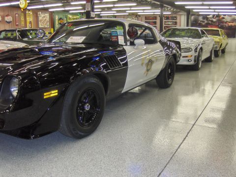 1979 Chevrolet Camaro - A black and white 1979 Chevrolet Camaro police car is parked in a showroom with other cars.
