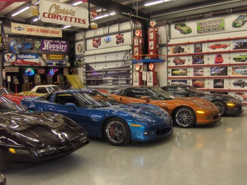1979 Chevrolet Camaro - A collection of modern Corvettes displayed in a garage filled with classic automotive memorabilia.