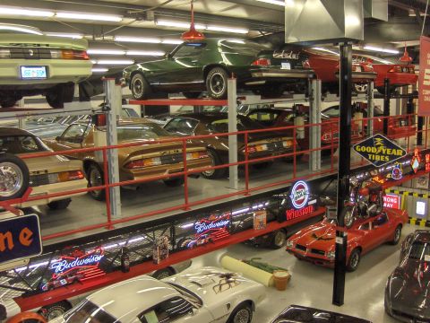 1979 Chevrolet Camaro - Several classic cars are displayed on multi-level racks in a garage setting.
