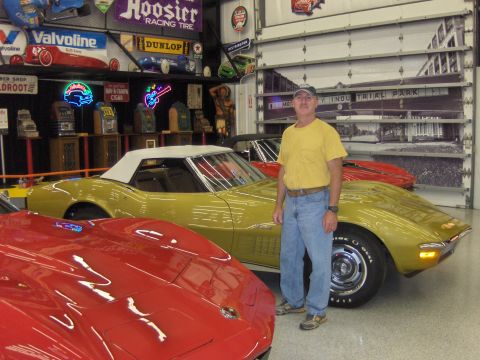 1979 Chevrolet Camaro - A man stands next to a yellow convertible Corvette in a garage filled with memorabilia and other cars.