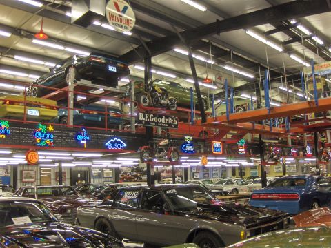 1979 Chevrolet Camaro - A busy showroom displays numerous vehicles and motorcycles, some elevated on racks.