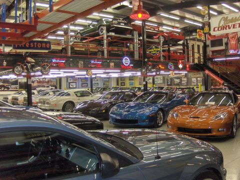 1979 Chevrolet Camaro - A collection of sports cars are displayed in a multi-level showroom with various memorabilia on the walls.