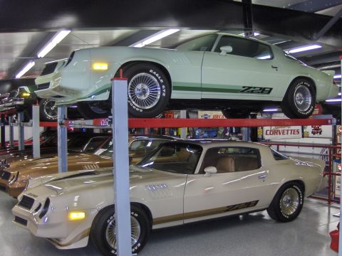 1979 Chevrolet Camaro - Two Chevrolet Camaros, a cream Z28 and a light green Z28, are displayed on car lifts.
