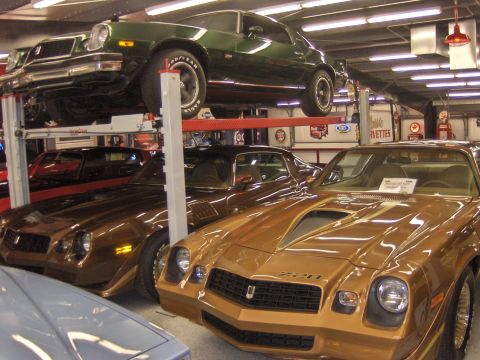 1979 Chevrolet Camaro - Multiple Chevrolet Camaros are displayed in a showroom, with one gold model prominently in the foreground.