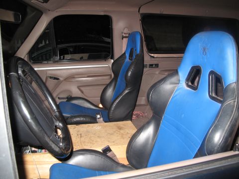 1995 Ford Bronco - The interior of a truck shows custom racing seats and an aftermarket steering wheel.