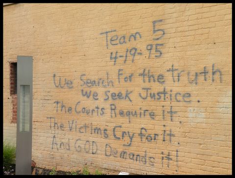 1998 Subaru Legacy - Graffiti spray-painted on a brick wall includes a date and a message about truth and justice.