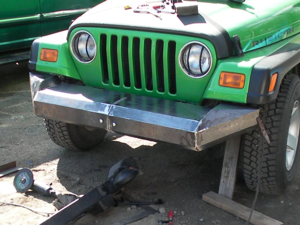 Green Jeep Wrangler with custom metal bumper and vertical grille