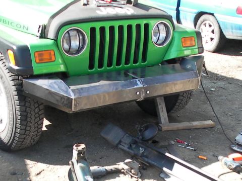 1987 Suzuki Samurai - Front view of a green Jeep showing its grille and custom bumper, with another vehicle in the background.