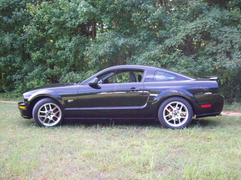 1973 Ford Maverick - Side view of a black 2005 Ford Mustang GT coupe.