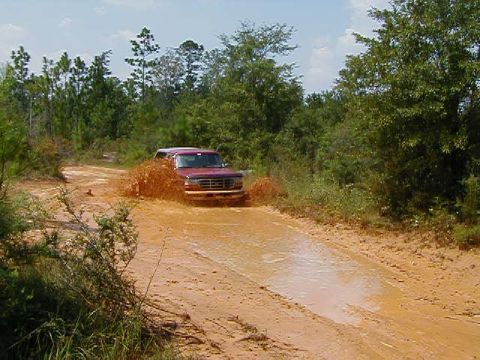 1990 Ford Bronco - This 1990 Ford Bronco navigates a muddy trail, kicking up a large spray of water.