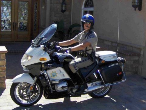 1991 Ford Crown Victoria - A police officer sits astride a white motorcycle, ready for duty.