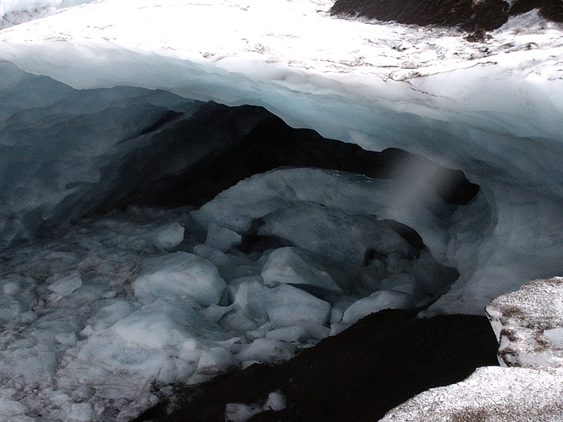 Blue glacial ice cave with broken ice blocks and snow