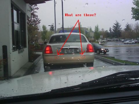 2000 Mercury Grand Marquis - A gold sedan is seen from behind, with a license plate and red taillights. Another vehicle is visible in the background.