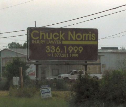 2000 Mercury Grand Marquis - Billboard advertising Chuck Norris Injury Lawyer with contact numbers is seen above a white pickup truck.
