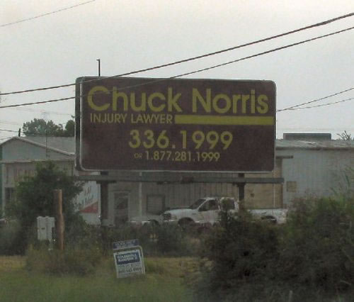 Billboard for Chuck Norris Injury Lawyer with phone numbers 336.1999 and 1.877.281.1999. A white pickup truck is visible behind the billboard