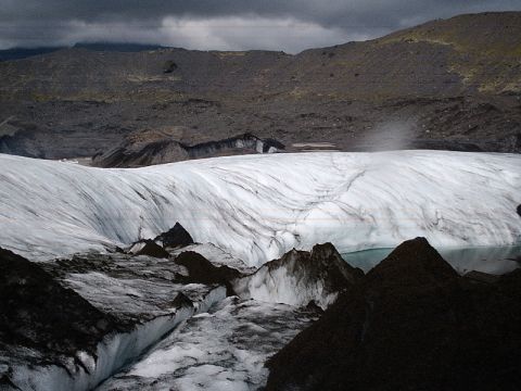 1996 Ford Bronco - A vast glacier landscape shows layers of ice and dark ash, with a small pool reflecting the overcast sky.