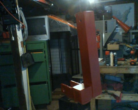 1987 Ford Bronco - A red metal part is visible in a workshop setting with various tools and equipment.