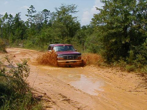 1990 Ford Bronco - This 1990 Ford Bronco kicks up a large splash as it navigates a muddy trail.