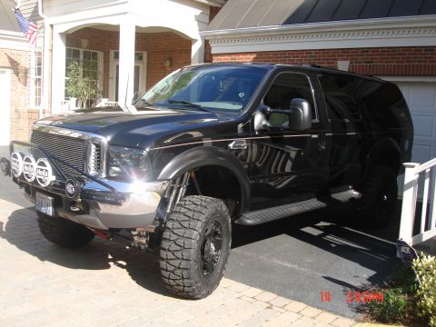 2000 Ford Excursion - This modified SUV features a prominent grille and auxiliary lighting, parked in a driveway.