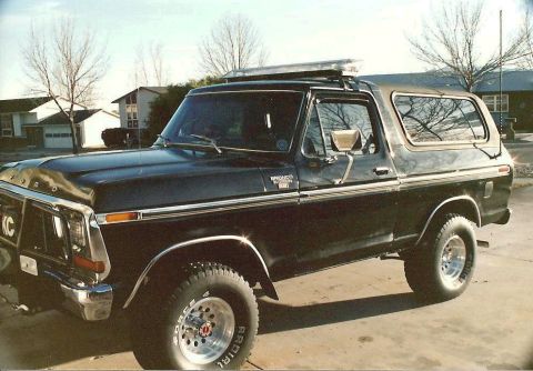 1978 Ford Bronco - A black Ford Bronco is parked in a driveway with houses in the background.