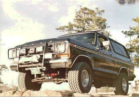 1978 Ford Bronco - A black 1978 Ford Bronco is shown with a brush guard and off-road tires, positioned on rocky terrain.