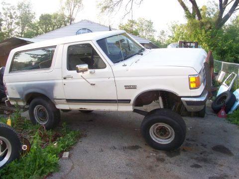 1989 Ford Bronco - This lifted Ford Bronco appears to be from the early 1990s, not 1989, and is parked in a driveway with some spare tires nearby.
