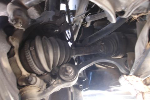1992 Ford Taurus - Undercarriage view of a CV axle boot and associated suspension parts, likely during a repair or inspection.