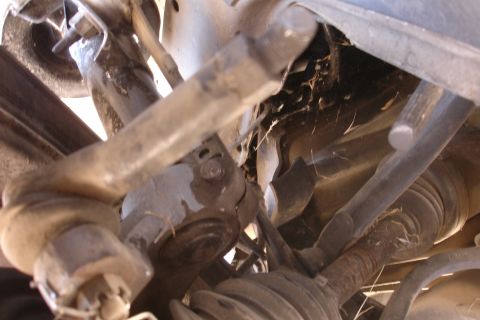 1992 Ford Taurus - Undercarriage view of a vehicle's suspension system, highlighting various mechanical components and a torn CV boot.