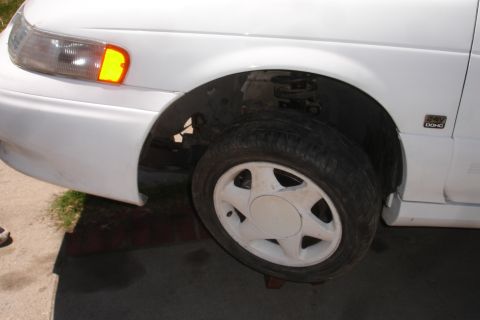 1992 Ford Taurus - Front fender and wheel of a white 1992 Ford Taurus, showing the 24V DOHC badge.