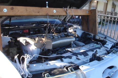 1992 Ford Taurus - Engine hoist supporting the V6 engine in the bay of a 1992 Ford Taurus during subframe replacement.