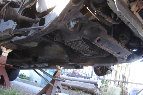 1992 Ford Taurus - Vehicle subframe and suspension components are visible from underneath, supported by jack stands.
