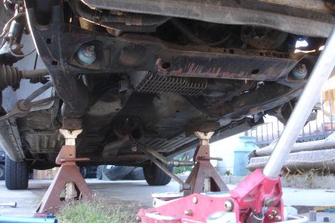 1992 Ford Taurus - The undercarriage of a vehicle is supported by jack stands, revealing the subframe and suspension components.