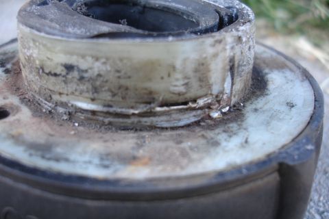 1992 Ford Taurus - A close-up view of a damaged and dirty automotive component, likely a bearing or bushing, showing signs of wear and tear.