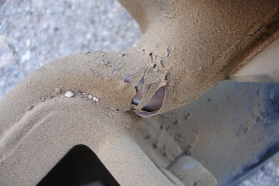 Close-up of heavily rusted and corroded metal tubing, possibly part of a vehicle's subframe