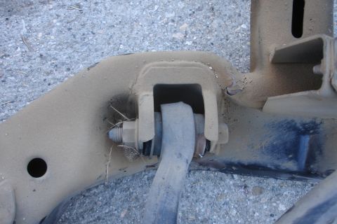 1992 Ford Taurus - A close-up view of a dusty, tan-colored metal suspension part, likely from a vehicle's subframe.