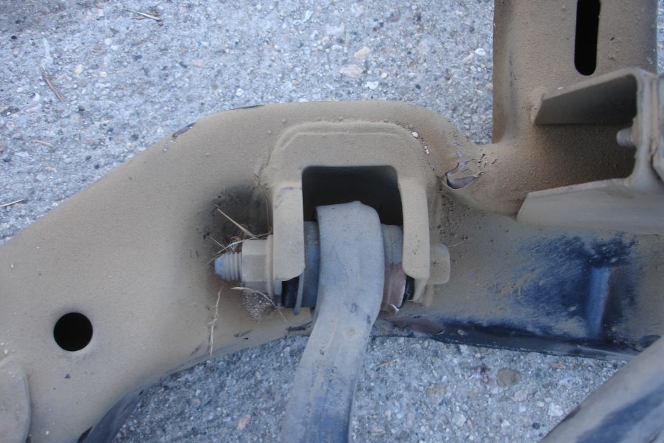 Close-up of a dusty metal suspension component with a bolt and bushing