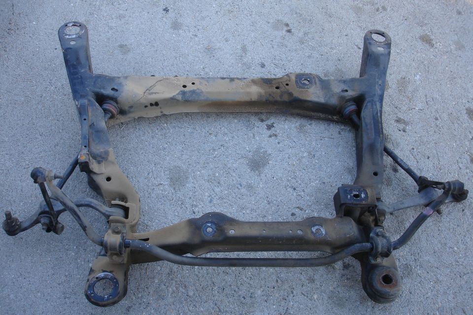 Front subframe assembly with suspension components attached, resting on concrete