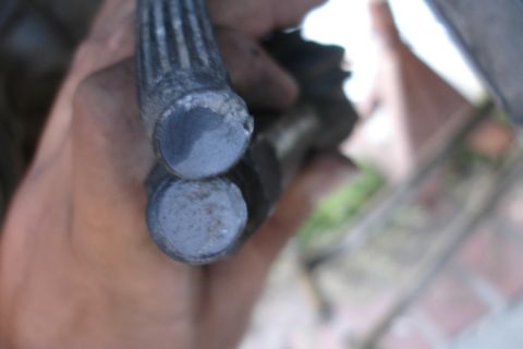 1992 Ford Taurus - Close-up view of two worn metal rods, likely a component from a vehicle's subframe.