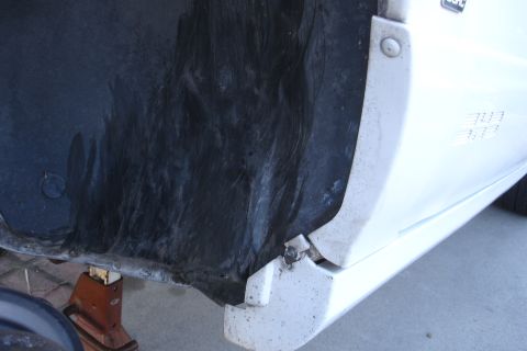 1992 Ford Taurus - Close-up view of a vehicle's wheel well liner and side panel, possibly undergoing subframe replacement.