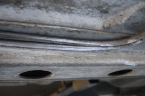 1992 Ford Taurus - Close-up view of the undercarriage of a vehicle, showing structural components and some wear.