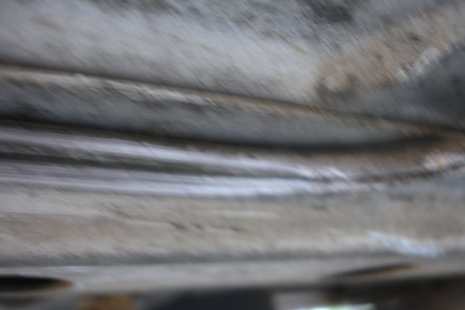 Undercarriage of a vehicle showing metal beams and some circular openings