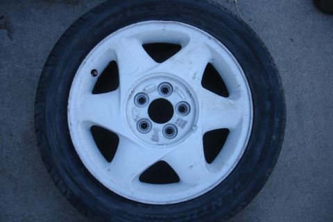 1992 Ford Taurus - A close-up view of a single car wheel and tire assembly resting on a textured surface.