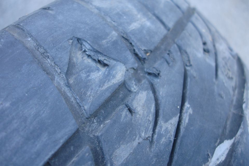 Close-up of a worn tire tread with chunks missing from the rubber