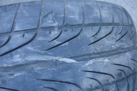 1992 Ford Taurus - The tire tread shows significant wear and damage, with several pieces missing from the rubber.