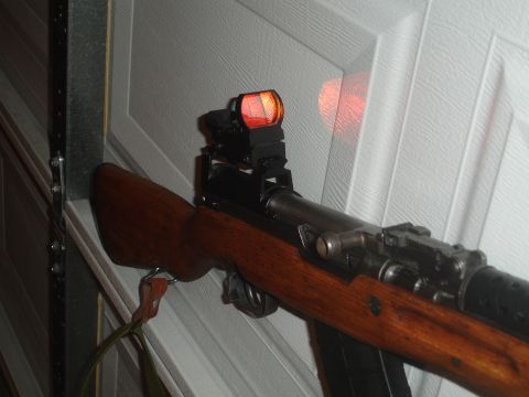 1989 Ford Bronco - A rifle with a wooden stock and a red dot sight is shown against a textured background.