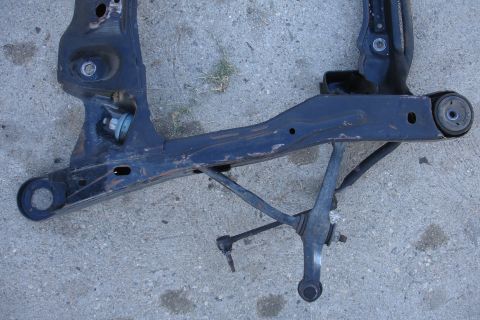 1992 Ford Taurus - A detached subframe assembly, likely for a vehicle, rests on a concrete surface.