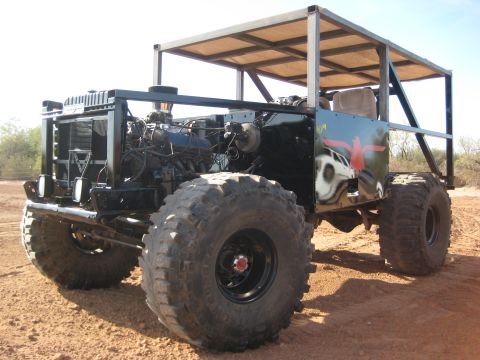 1996 Ford Bronco - This custom-built vehicle features oversized tires and an exposed engine bay, with a metal frame for a roof.