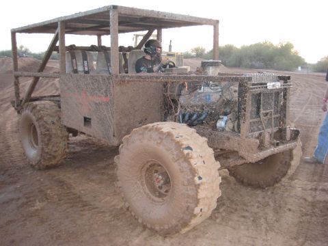 1996 Ford Bronco - A heavily modified off-road vehicle covered in mud sits in a dirt track.