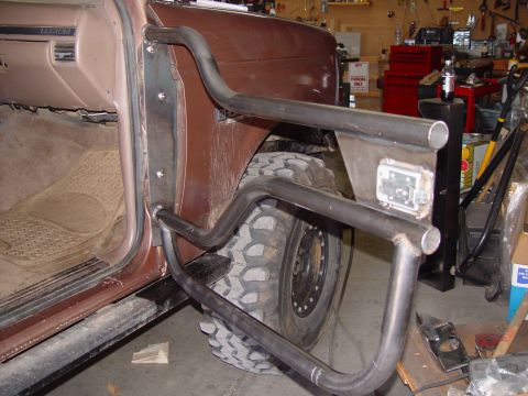 1993 Ford Bronco - In-progress fabrication of a bare-steel tube door tacked to the driver's opening of a brown Ford truck in a home garage, with the door skin…